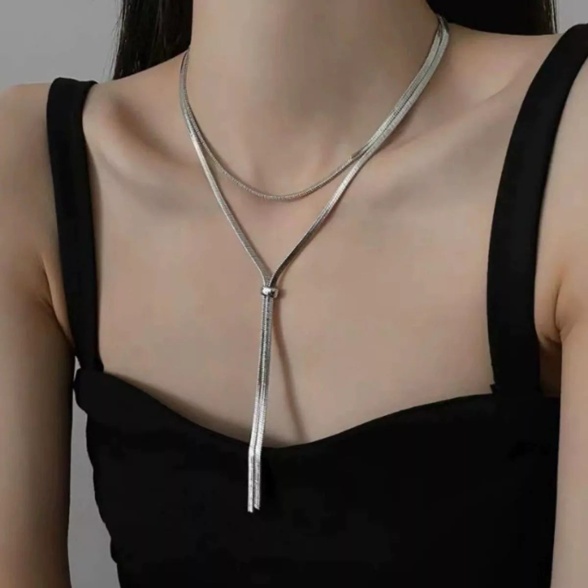 Necklace with tassels worn by a person against a neutral background