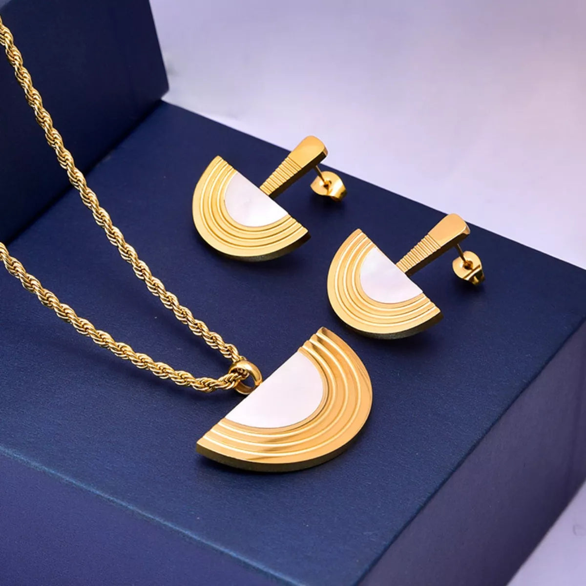 Gold and white jewelry set on a blue box