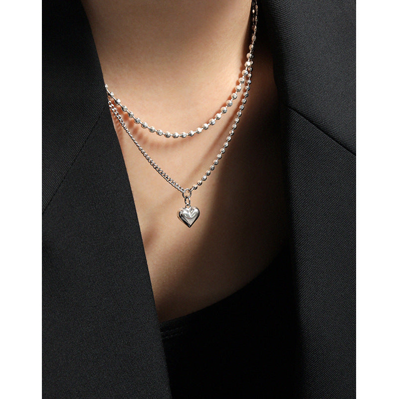 Necklace with a heart pendant worn by a person in a black outfit