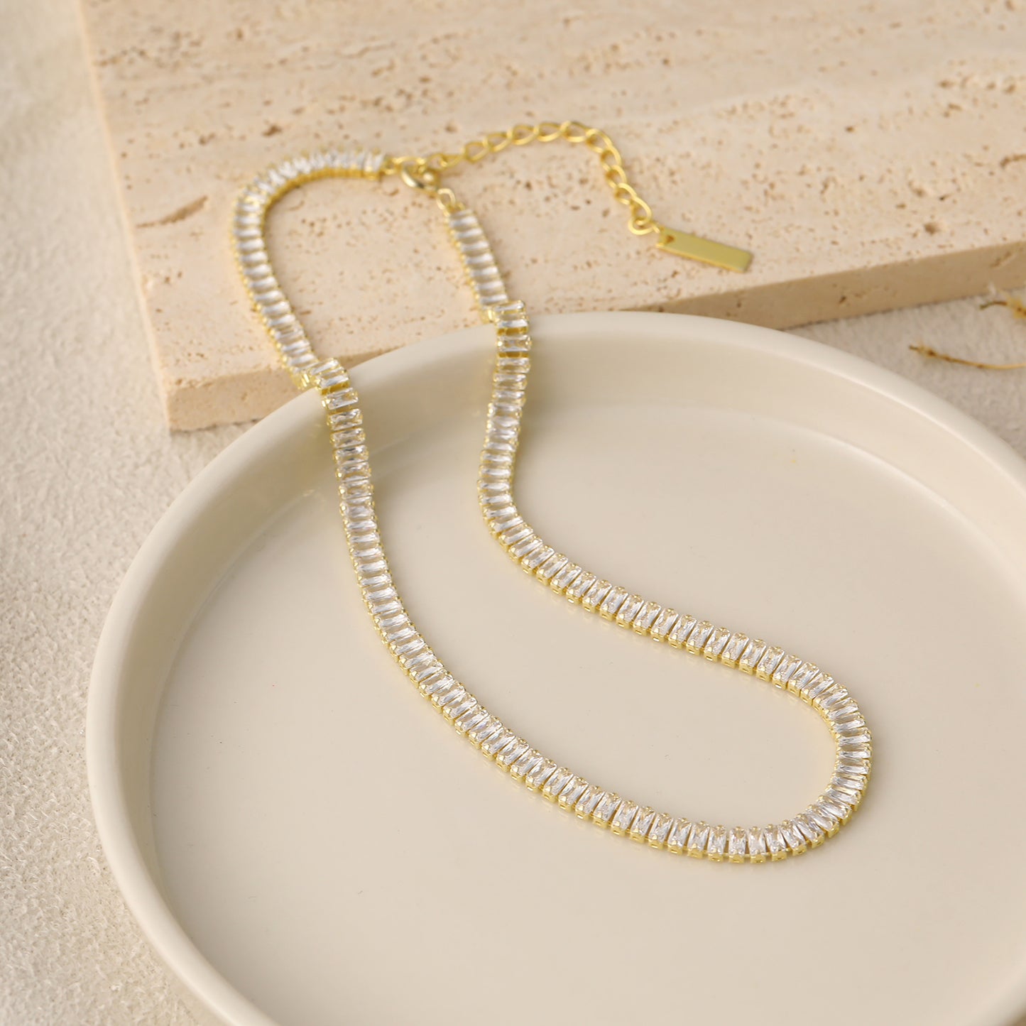 Gold and silver beaded necklace on a beige plate with a neutral background