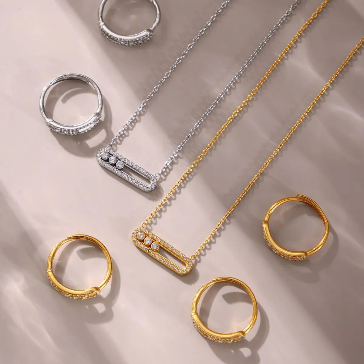 Gold and silver jewelry including rings and a necklace on a beige background