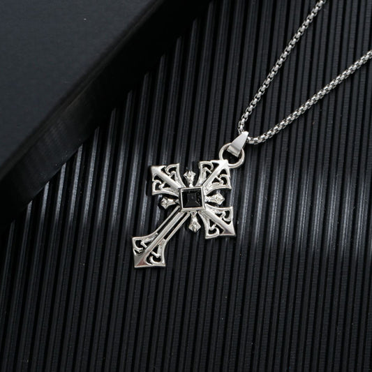 Silver cross pendant necklace on a textured black surface