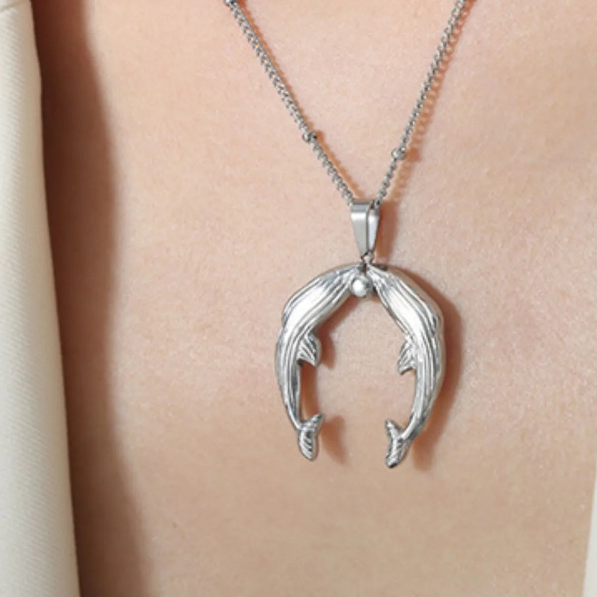 Silver necklace with a dolphin pendant on a person's neck
