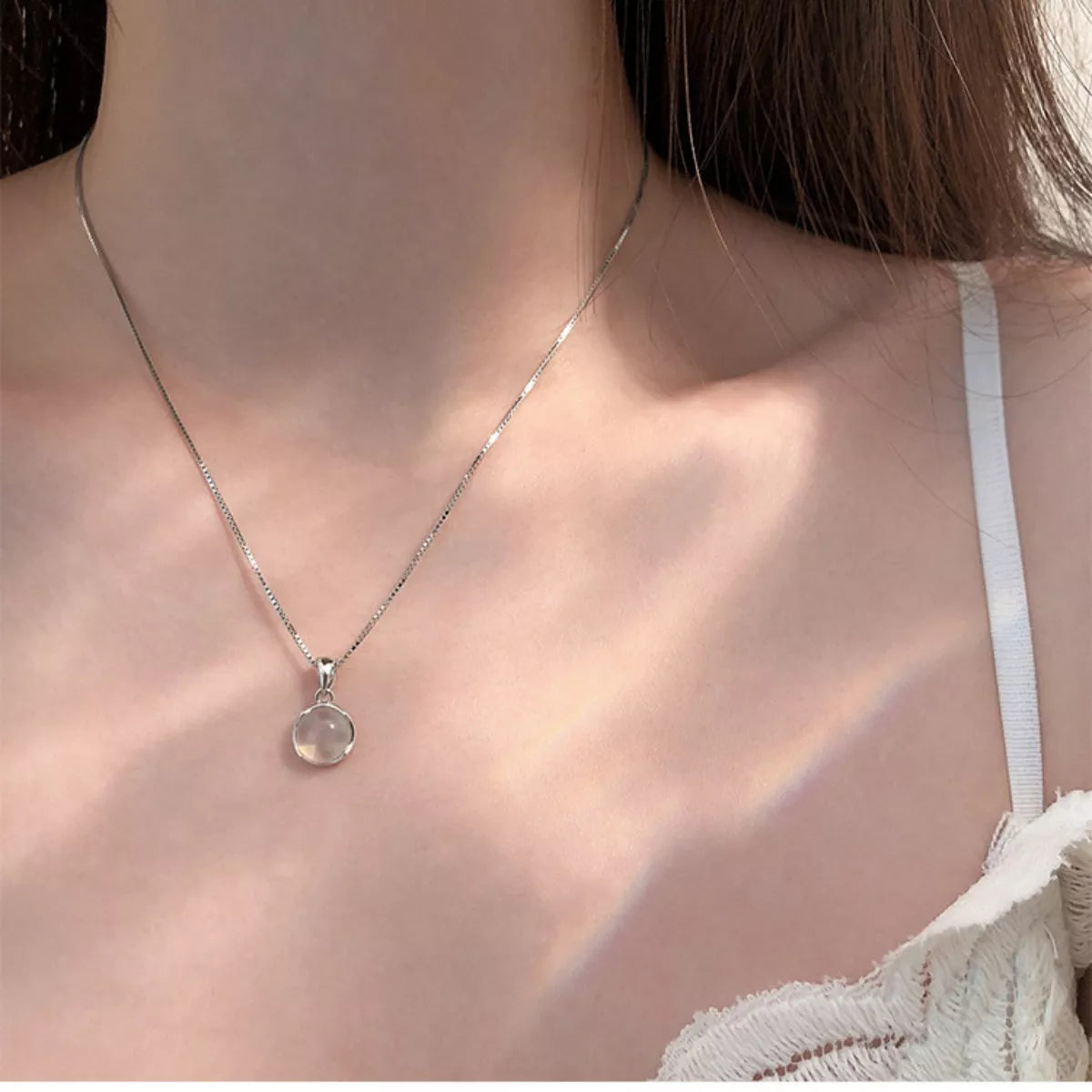 Necklace with a pendant worn by a person, focusing on the jewelry.