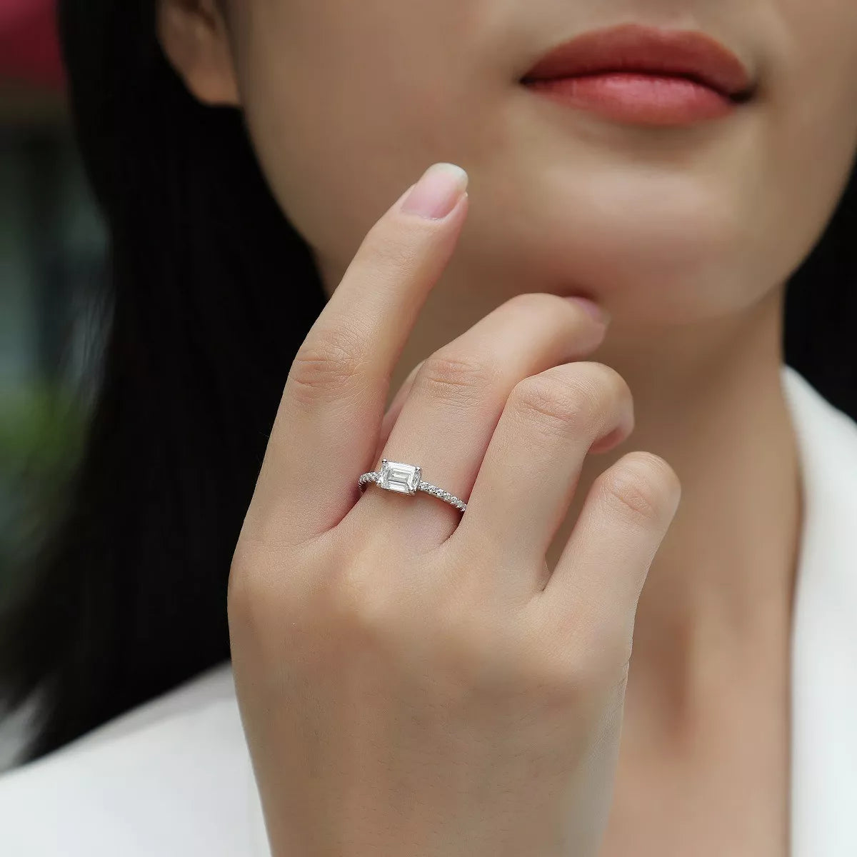 Close-up of a hand wearing a diamond ring with a blurred background