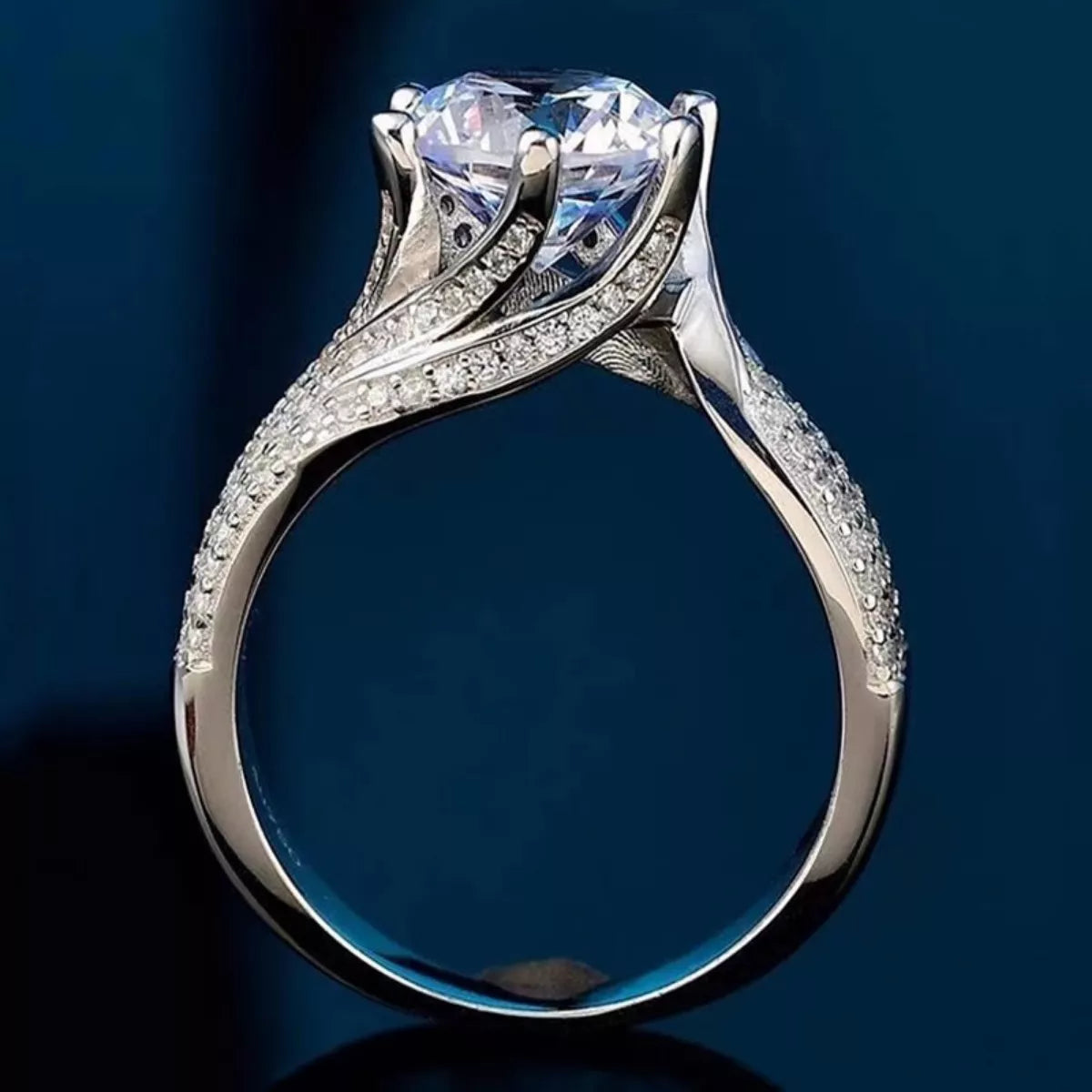 Silver ring with a large diamond and smaller diamonds on a dark blue background