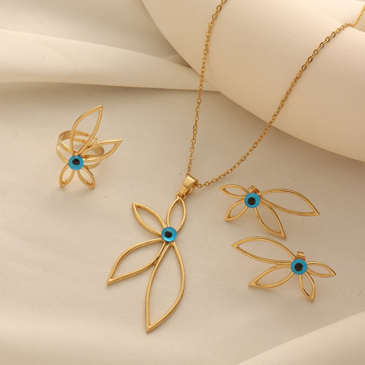 Gold-tone flower jewelry set with a blue enamel evil eye necklace, matching ring, and earrings on a cream fabric background.