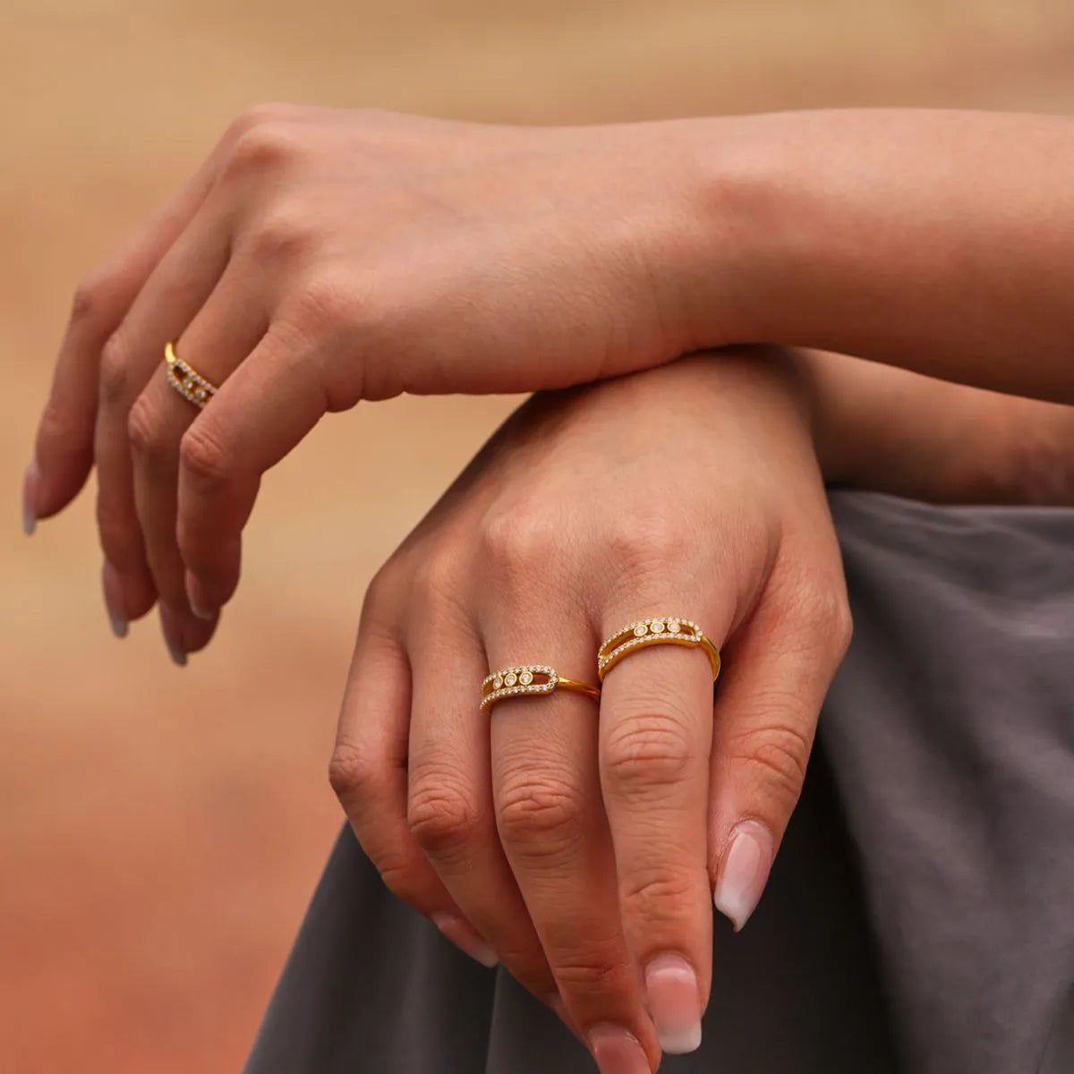 Close-up of hands wearing gold rings on a warm-toned background