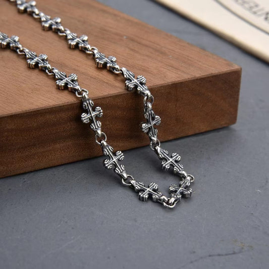 Silver chain necklace on a wooden block with a gray background