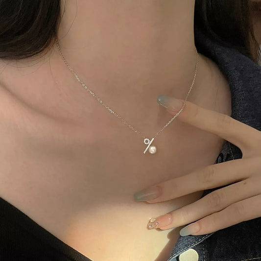 Necklace with a small pendant worn by a person, with a hand touching the neck.