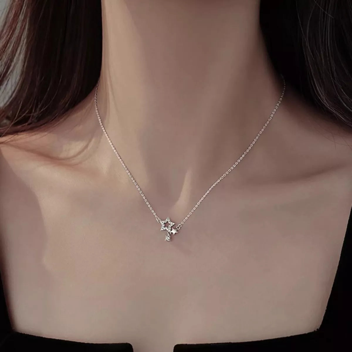 Silver necklace with a star pendant worn by a person
