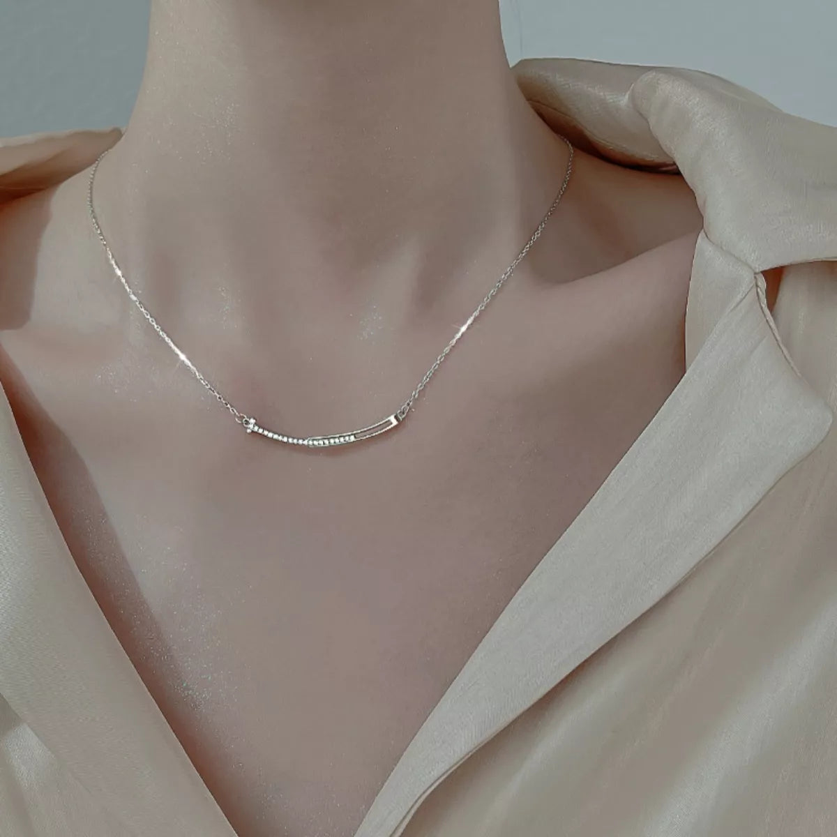 Silver necklace on a mannequin with a soft pink blouse
