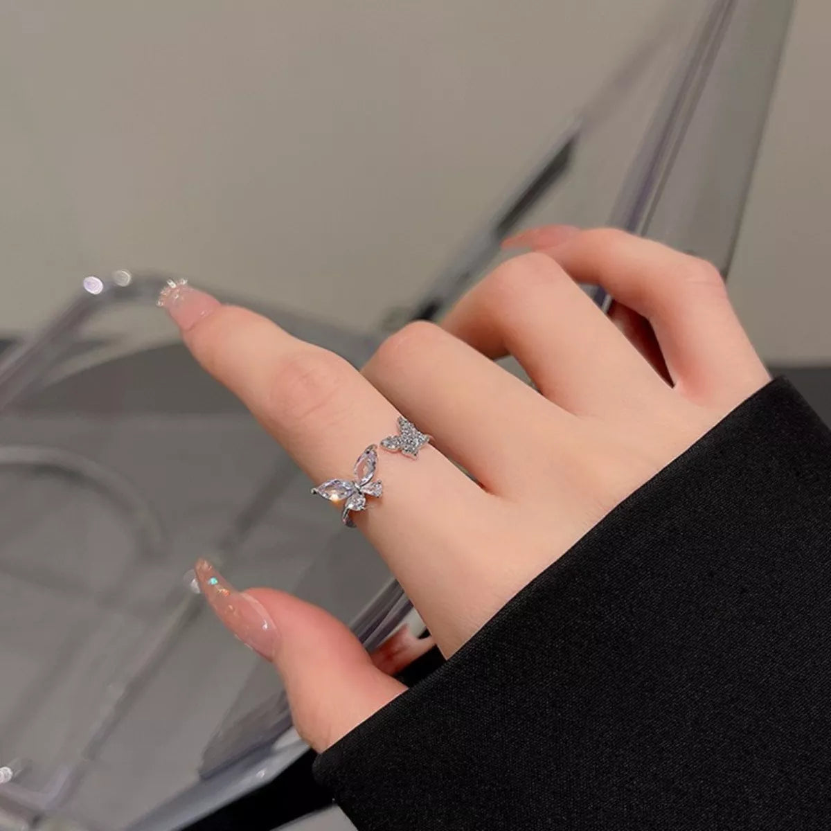 Hand wearing a butterfly-shaped ring with a blurred background