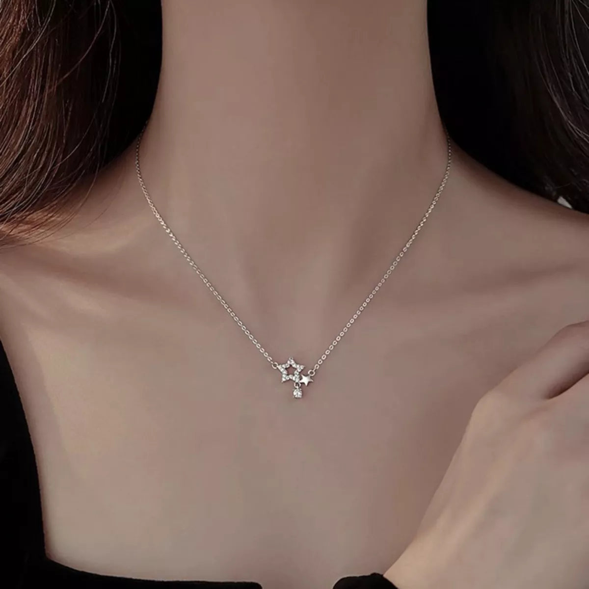 Silver necklace with a star-shaped pendant on a person's neck