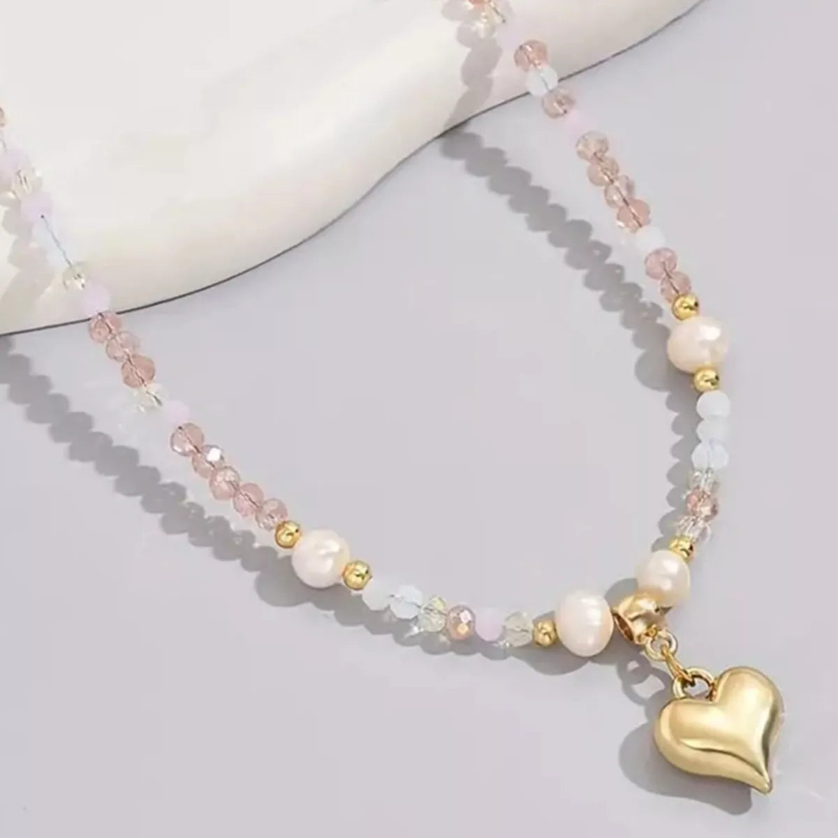 Necklace with heart charm and multicolored beads on a light background
