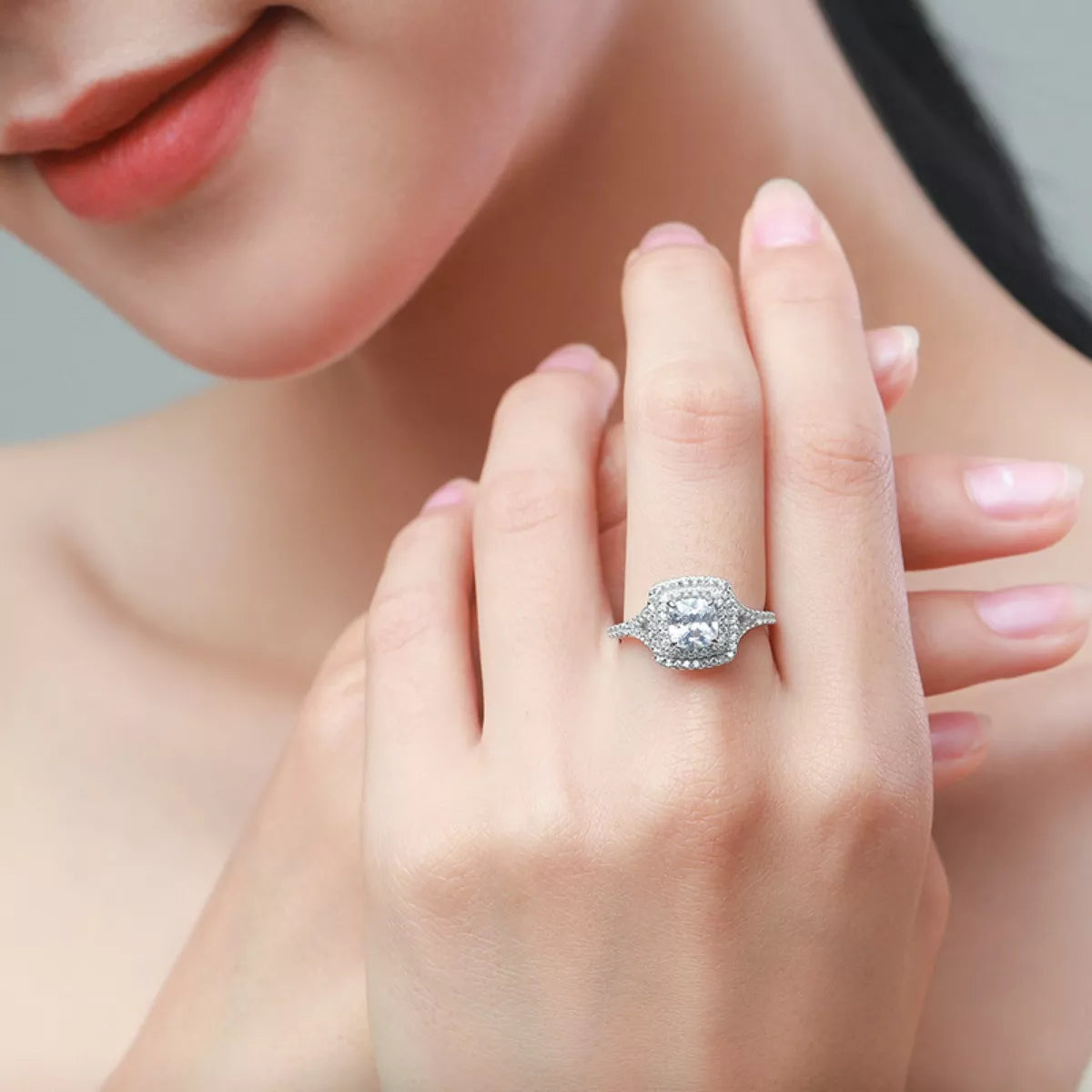 Close-up of a hand wearing a diamond ring with a blurred background