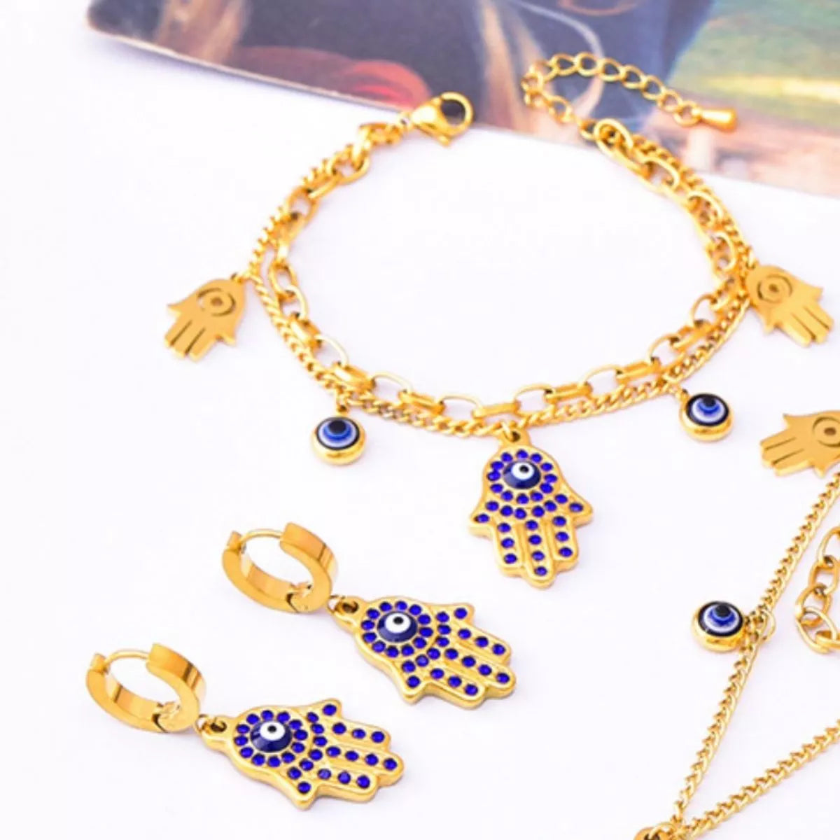 Gold and blue hamsa hand jewelry set on a white background