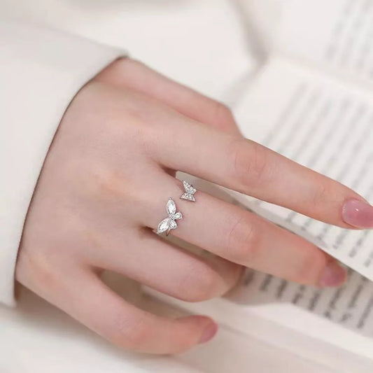 Hand wearing a silver ring with a butterfly design on a light background