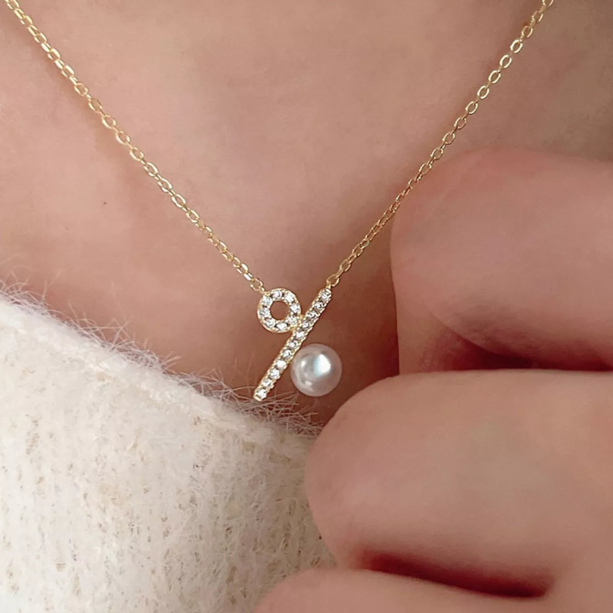 Gold necklace with a pearl pendant worn by a person