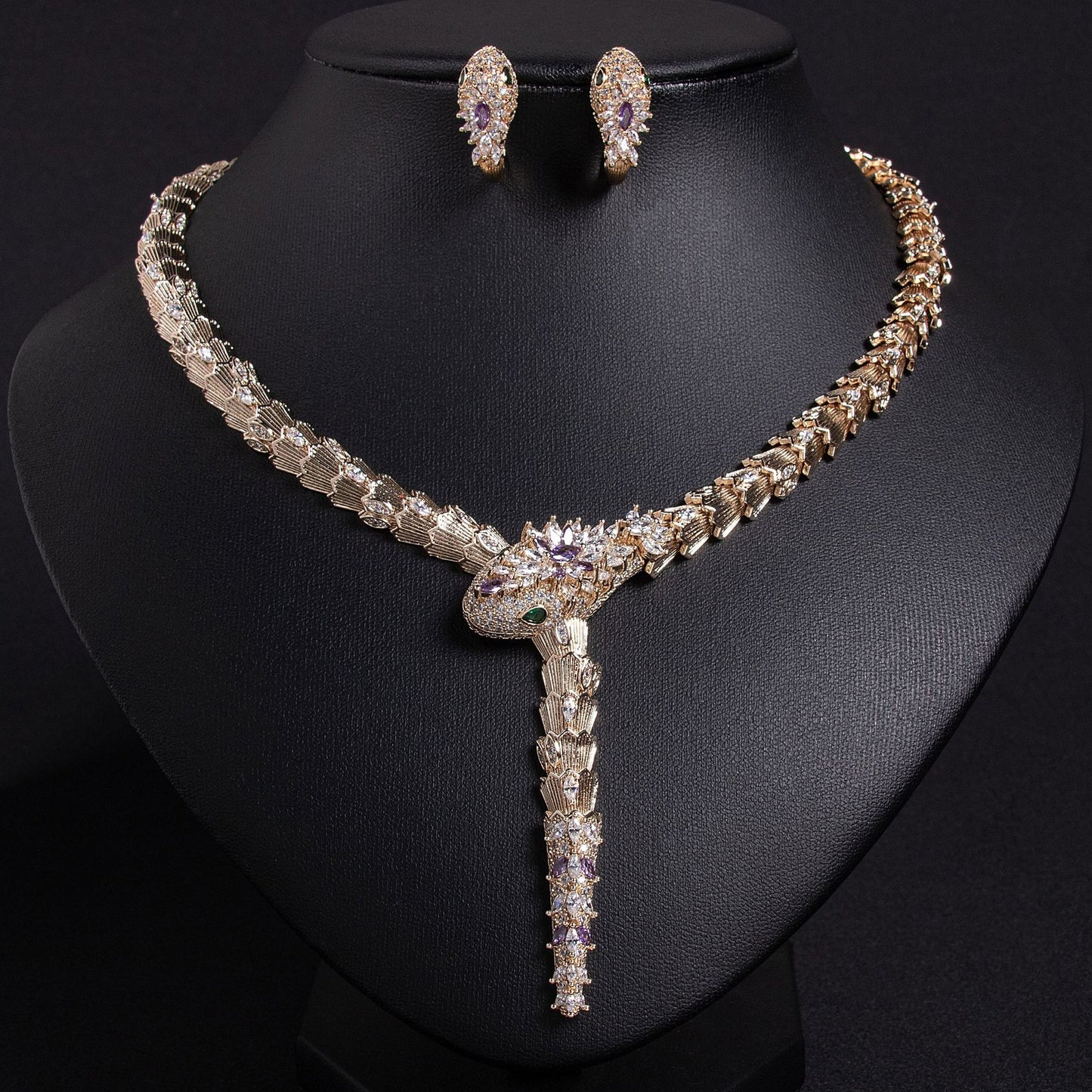Gold snake necklace and earrings set with purple and clear stones, on a black background.