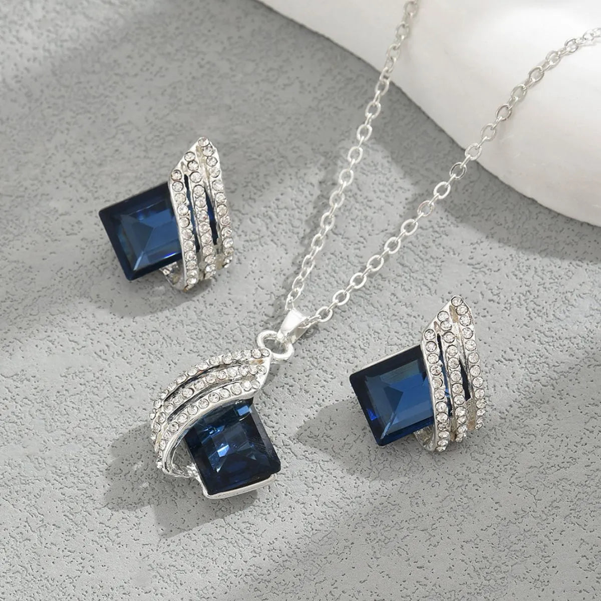 Silver jewelry set with blue gemstones on a gray surface