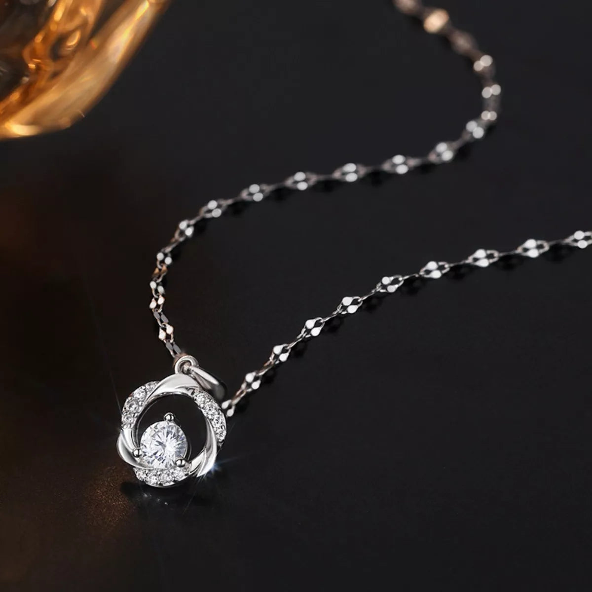 Silver necklace with a round pendant on a dark background