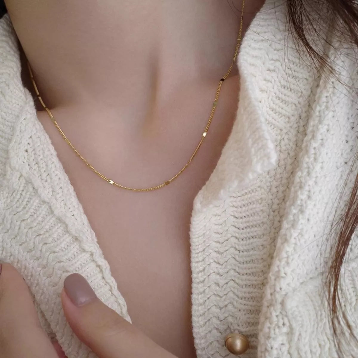 Gold necklace on a mannequin with a white textured garment
