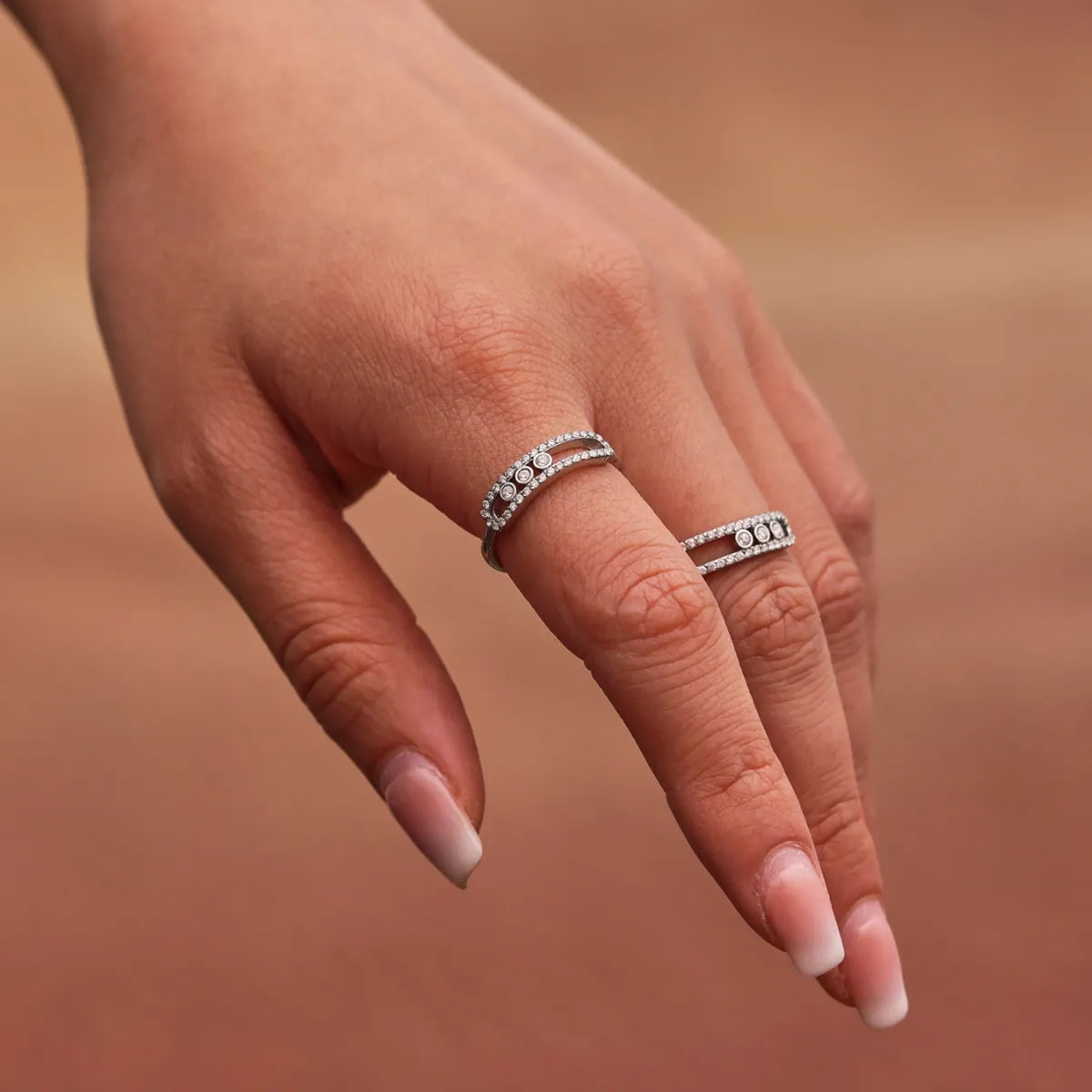 Hand wearing two silver rings with a blurred background