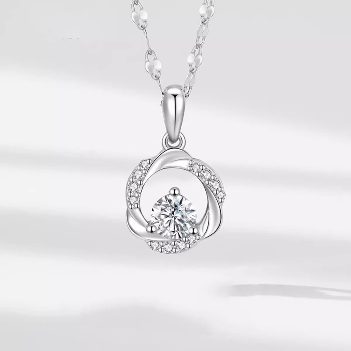Silver necklace with a round pendant on a light gray background