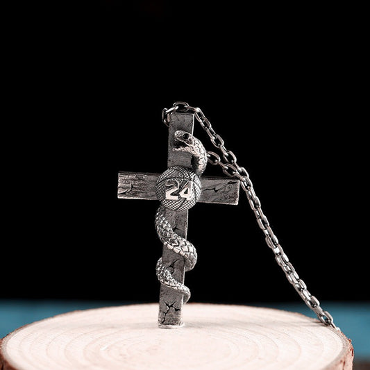Silver cross pendant with chain on a wooden stand against a black background