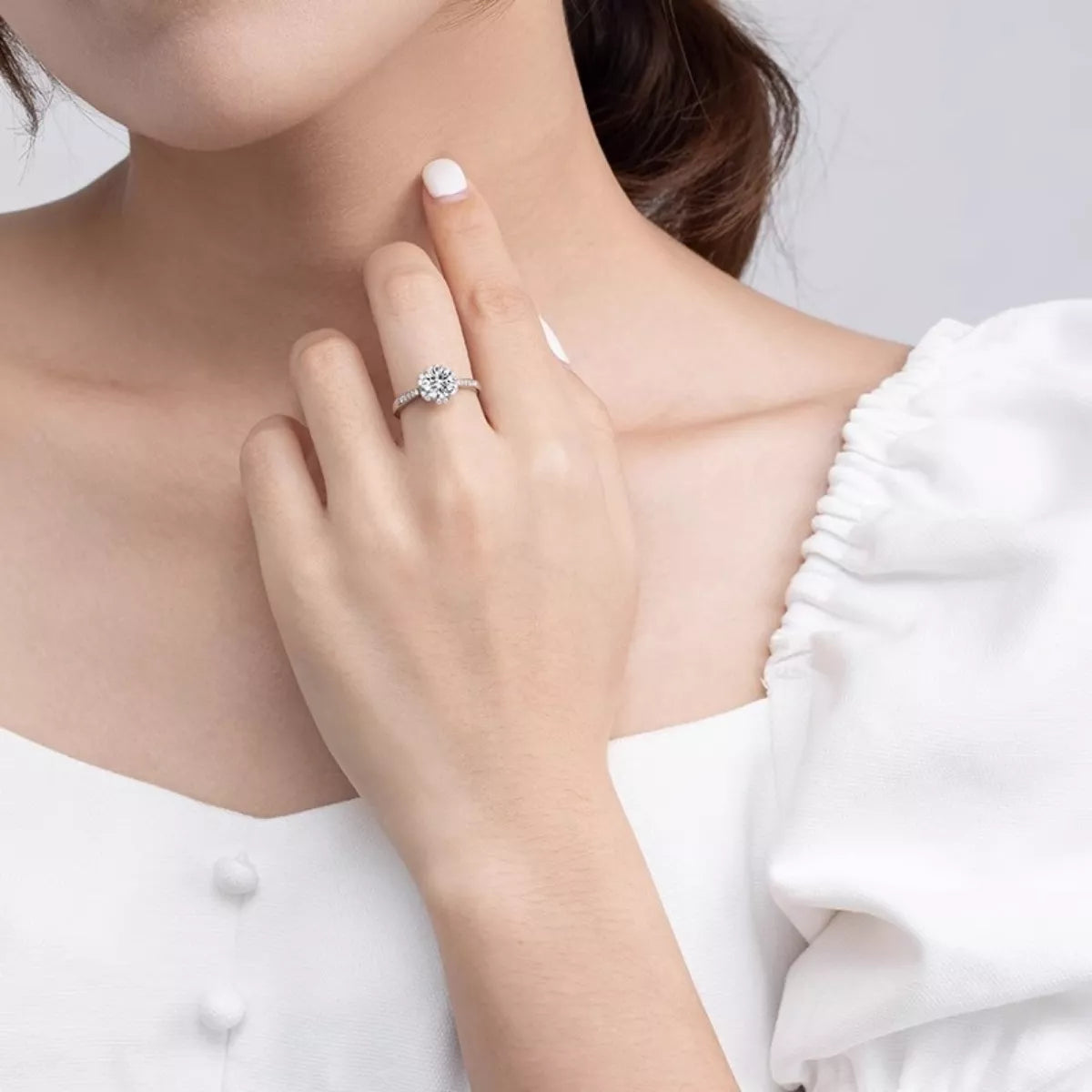 Close-up of a hand wearing a diamond ring on a white background