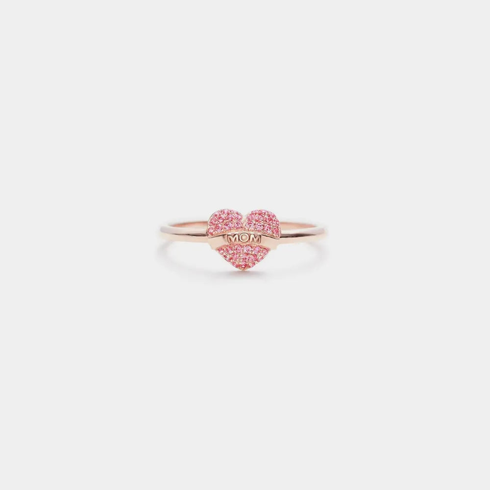 Heart-shaped ring with 'Mom' engraving on a light pink background
