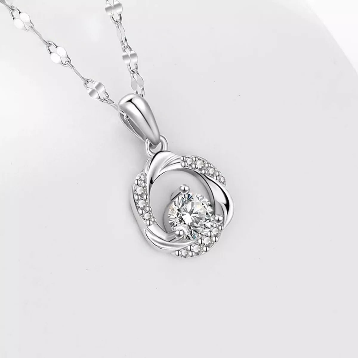 Silver heart-shaped pendant with a diamond on a light gray background