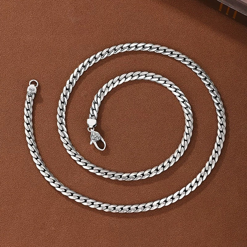 Silver chain necklace on a brown textured surface