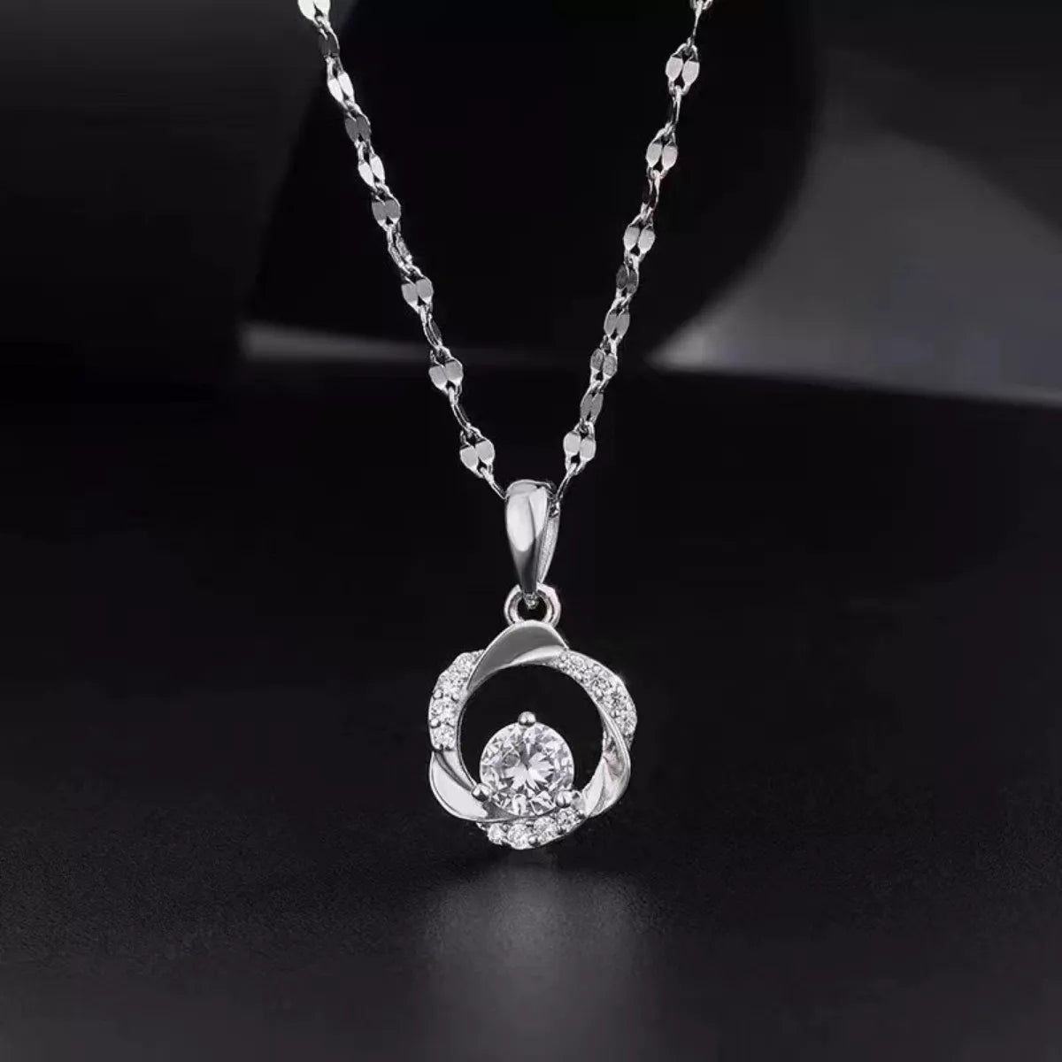 Silver necklace with a circular pendant on a dark background