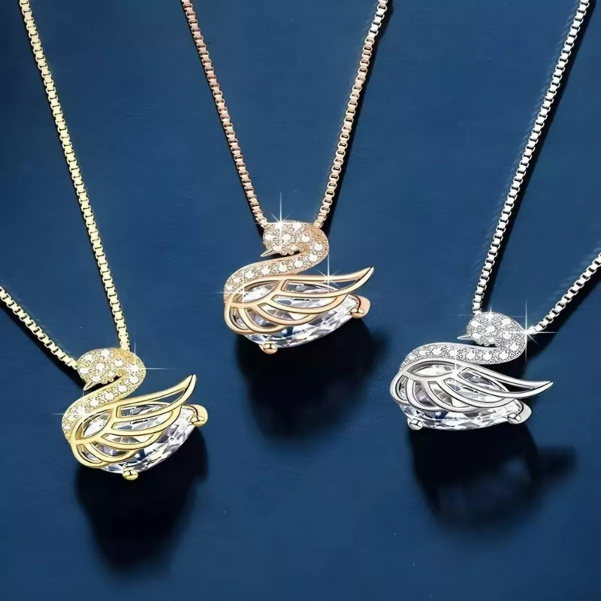 Three swan-shaped pendants on chains against a dark blue background