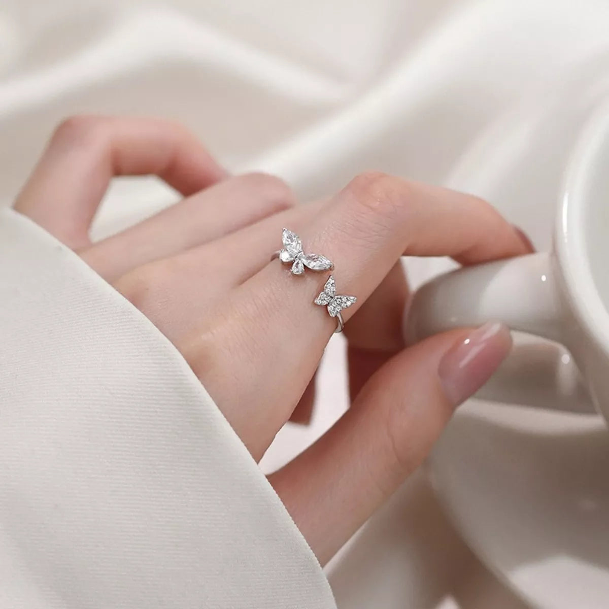 Butterfly-shaped silver ring on a hand with a soft background