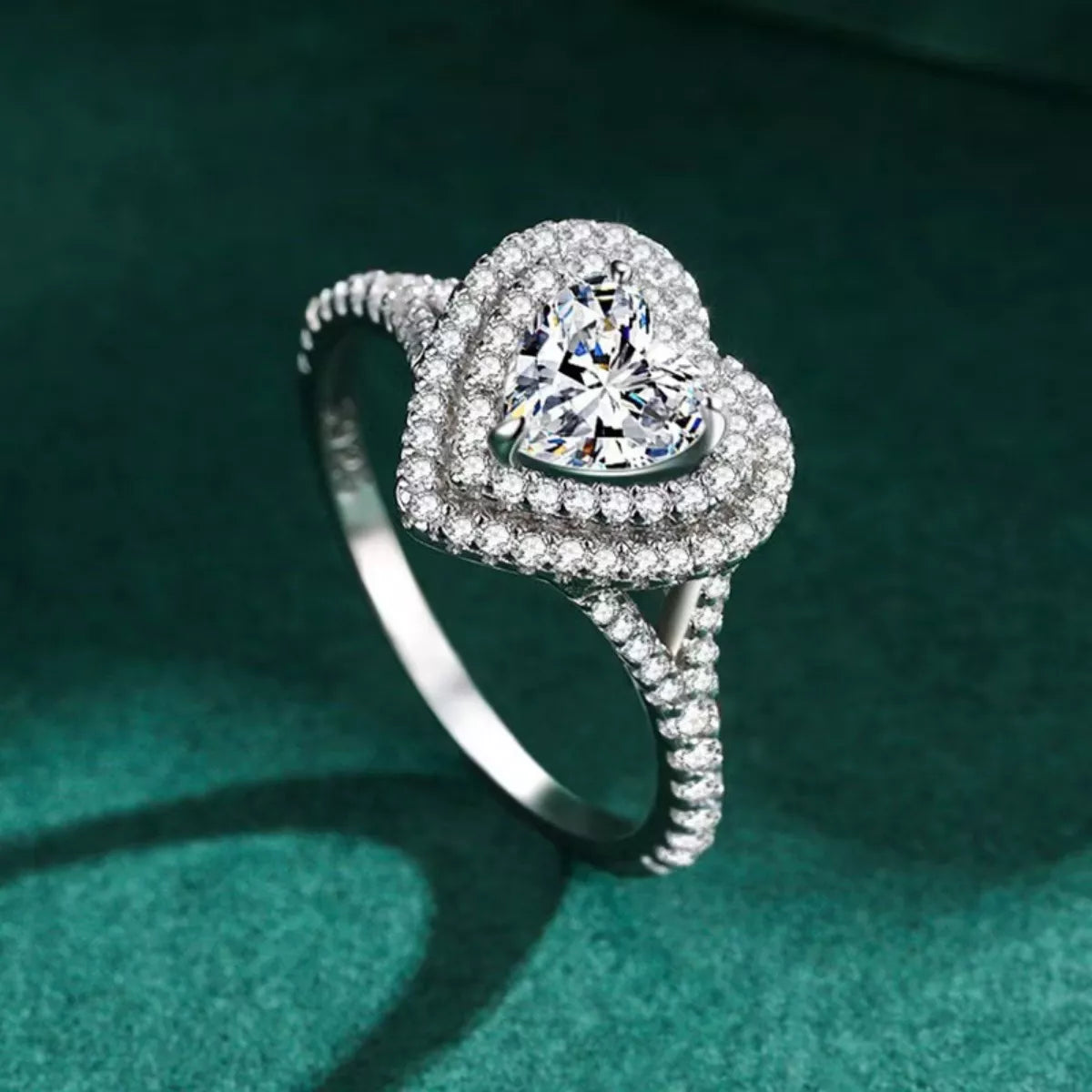 Silver ring with a heart-shaped diamond on a green background