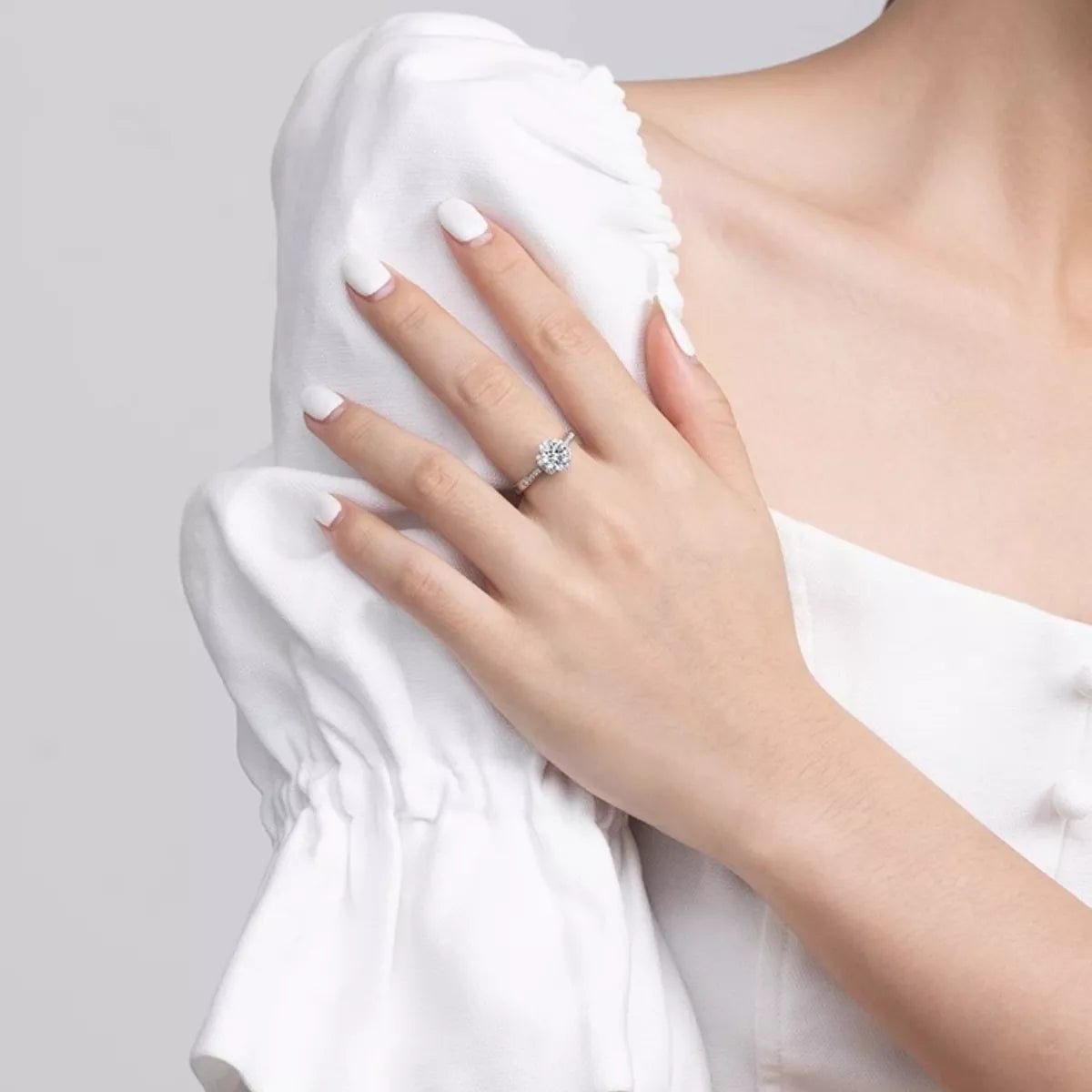 Hand wearing a diamond ring on a white background