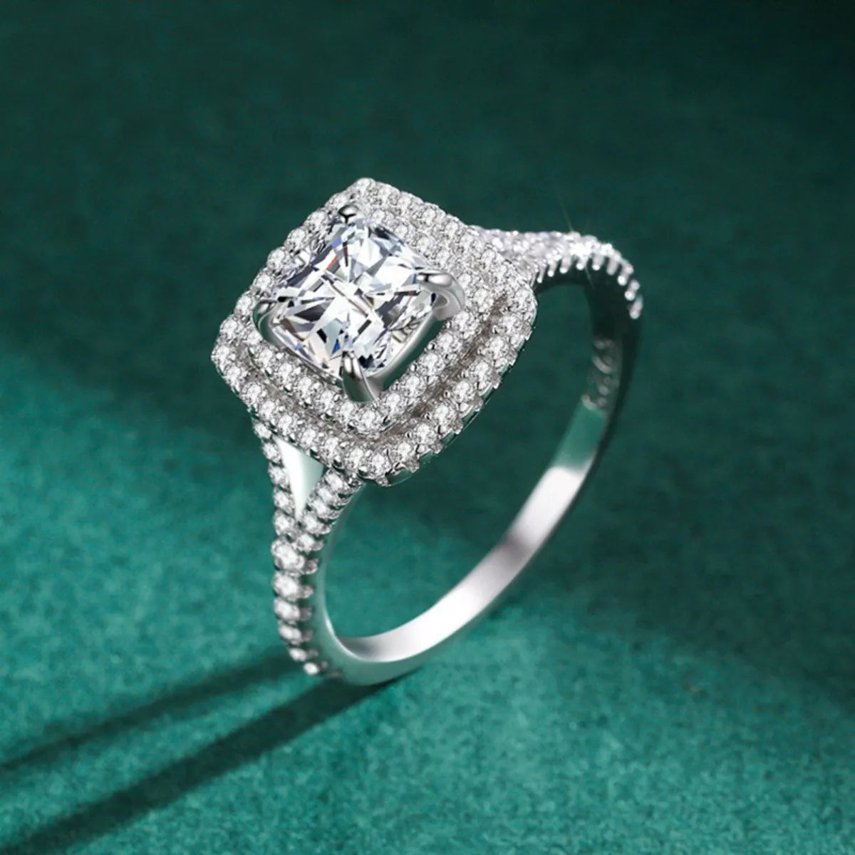 Silver ring with a large diamond and smaller diamonds on a green background
