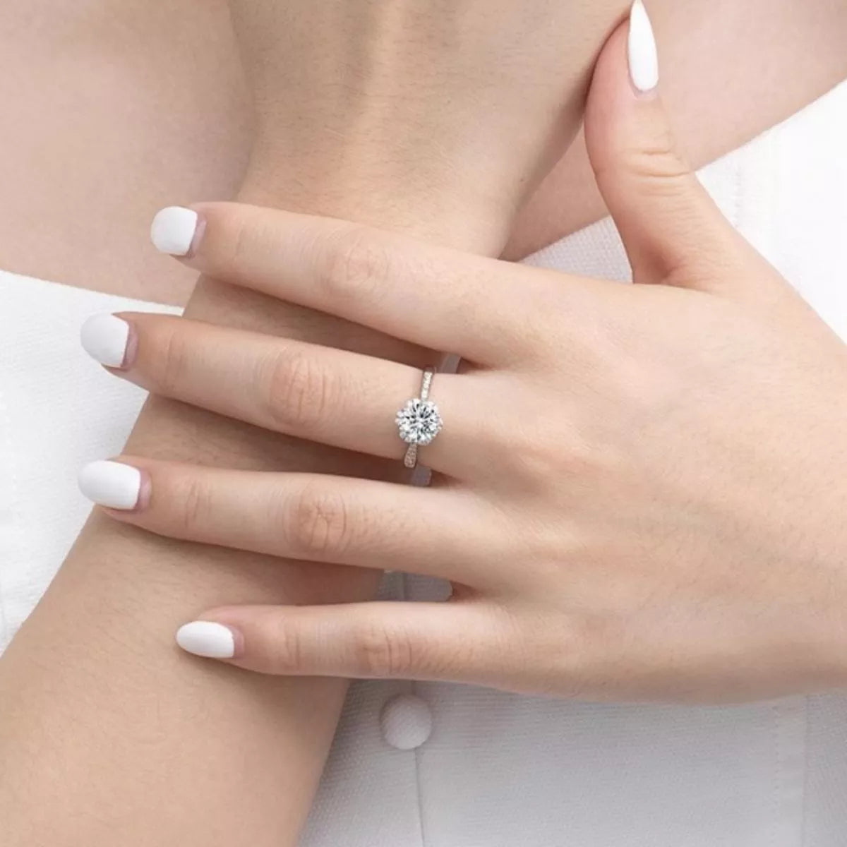 Hand wearing a diamond ring on a plain background