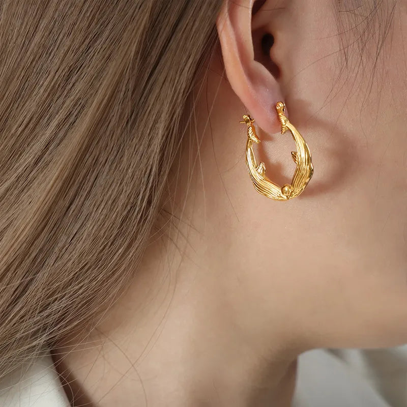 Gold hoop earring worn by a person with light brown hair.