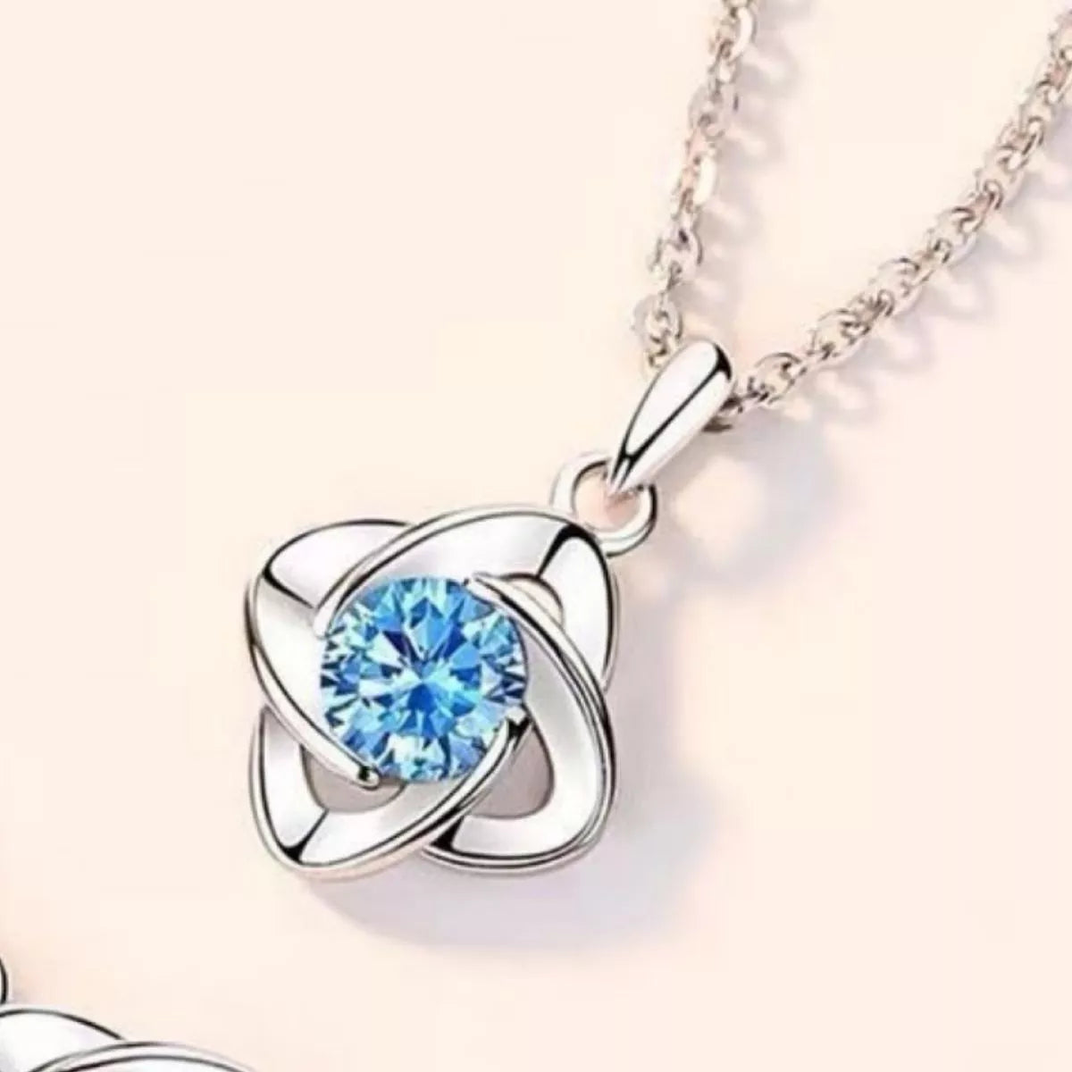 Silver necklace with a blue gemstone pendant on a light background