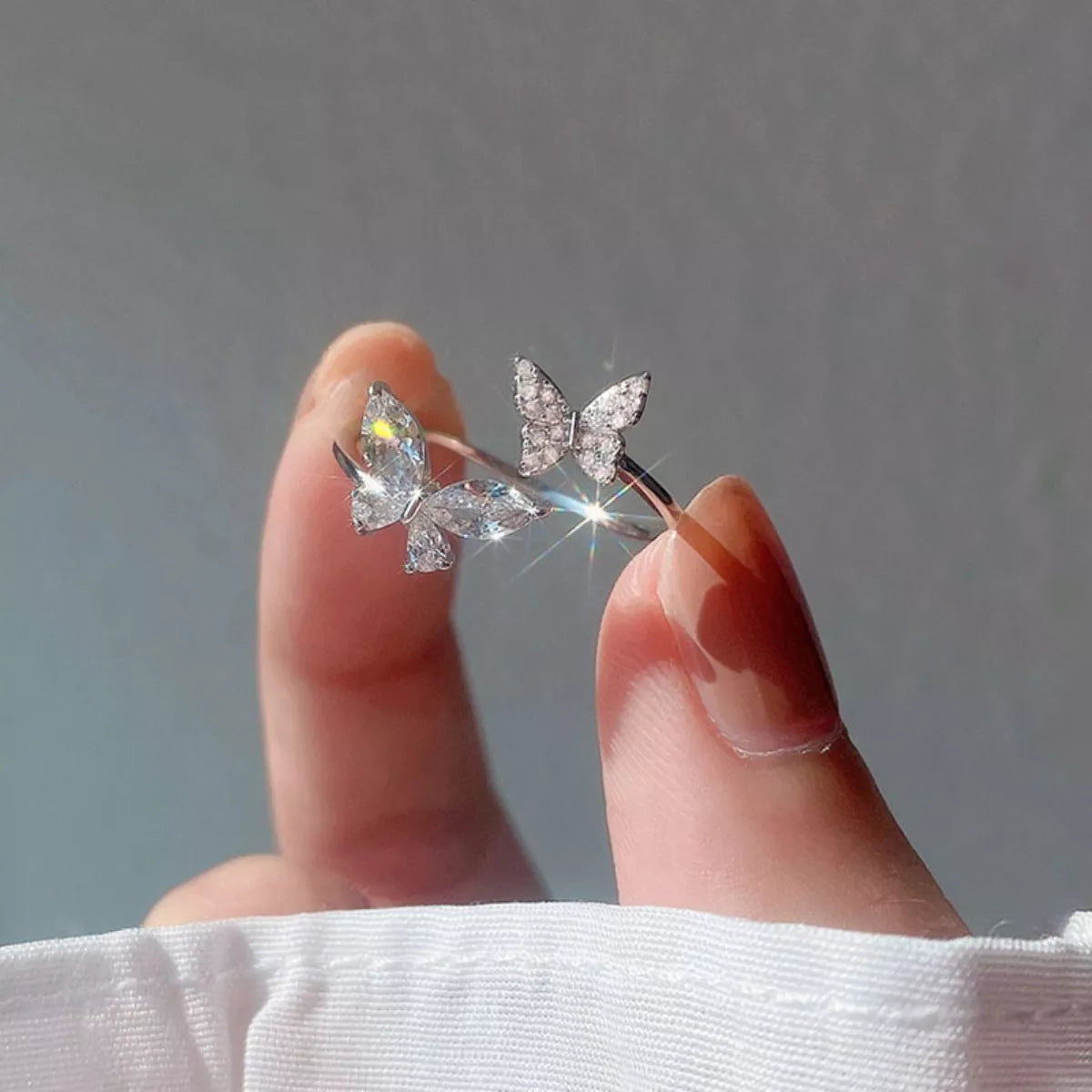 Butterfly-shaped earrings held between fingers against a neutral background