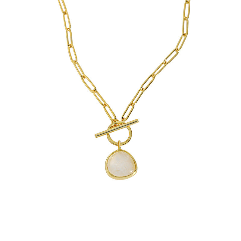Gold necklace with a white pendant on a white background