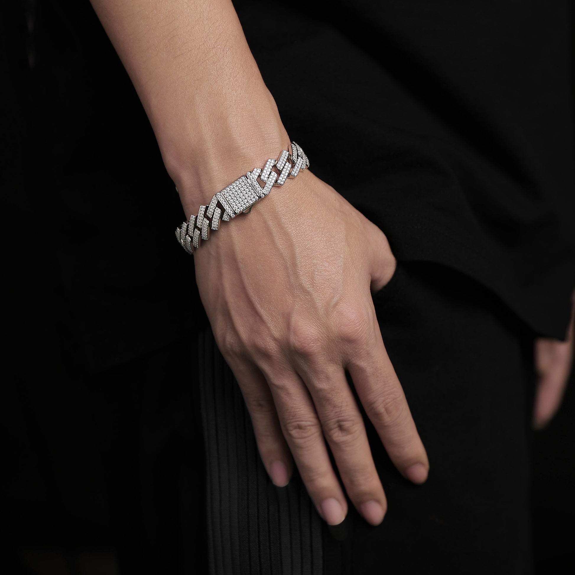 Hand wearing a diamond bracelet on a black background