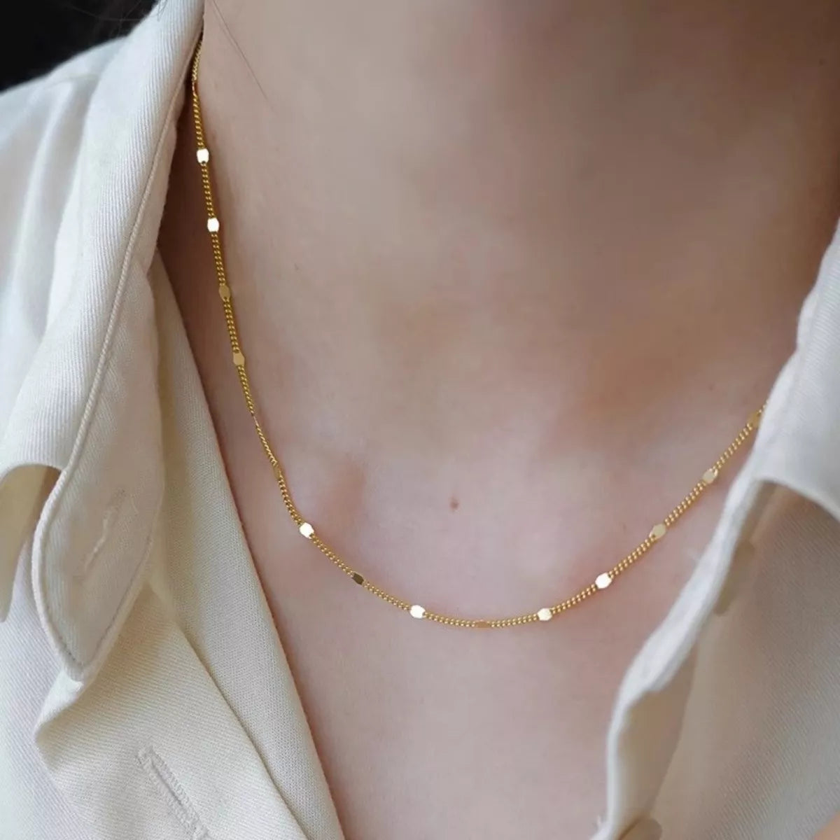 Gold necklace on a person wearing a white shirt