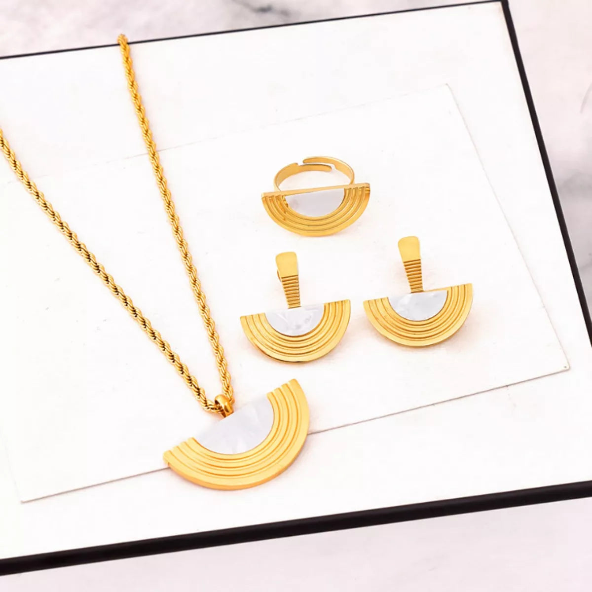 Gold necklace and earrings set on a white surface