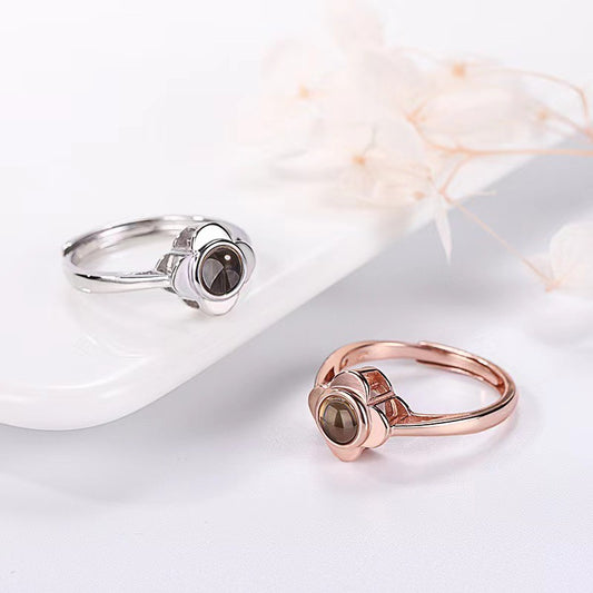 Two rings, one silver and one rose gold, on a white surface with a soft focus background.