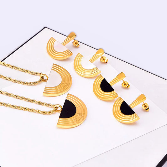Gold and black jewelry set including necklaces and earrings on a white background